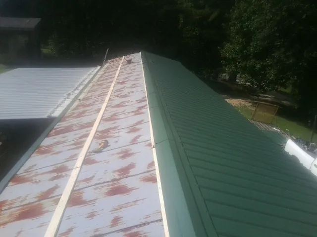 Old rusted panels beside newly installed green metal roofing — Wind Damage Roof Repair by Roofing Brothers in Shawnee